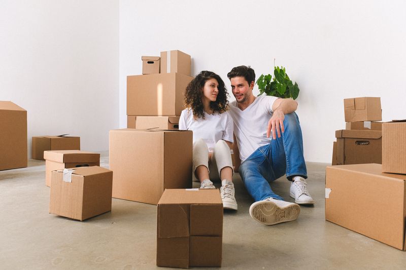 Couple souriant assis parmi les cartons de son nouveau logement